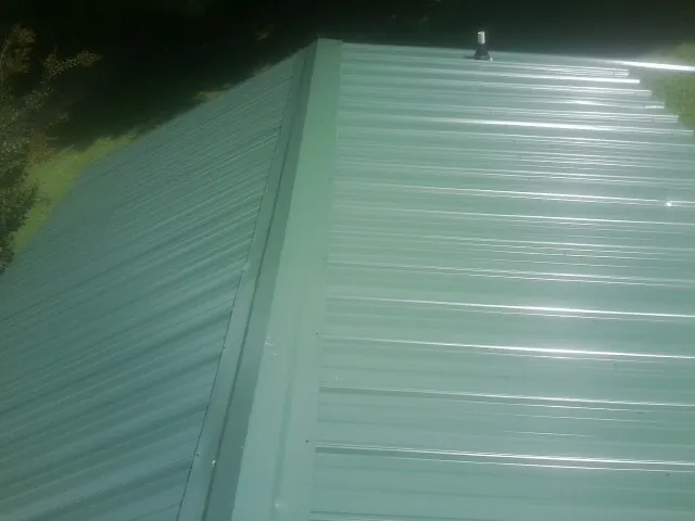 New green metal panels meeting at the ridge of a roof — Flat Roof Repair work by our crew in Naval Anacost Annex