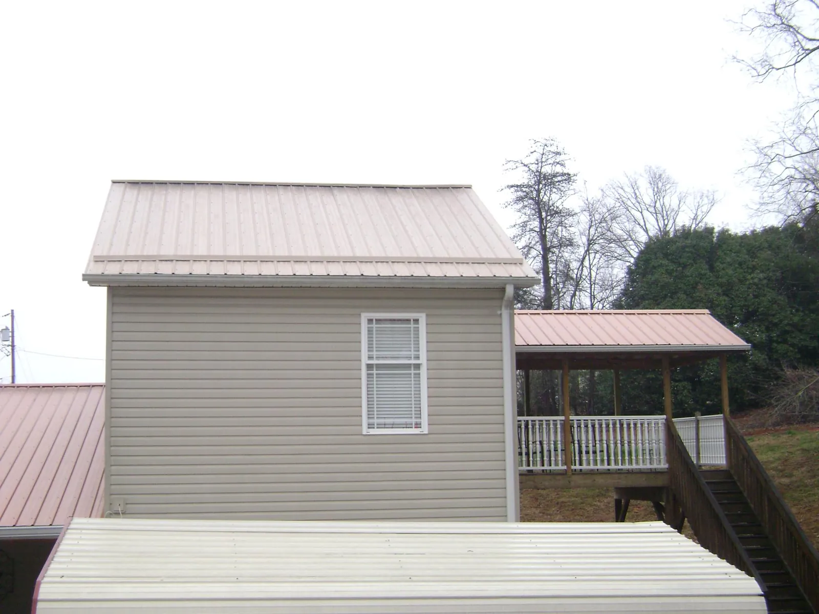 Tan metal roofs on a two story addition and attached porch, from a Roof Replacement job in Naval Anacost Annex